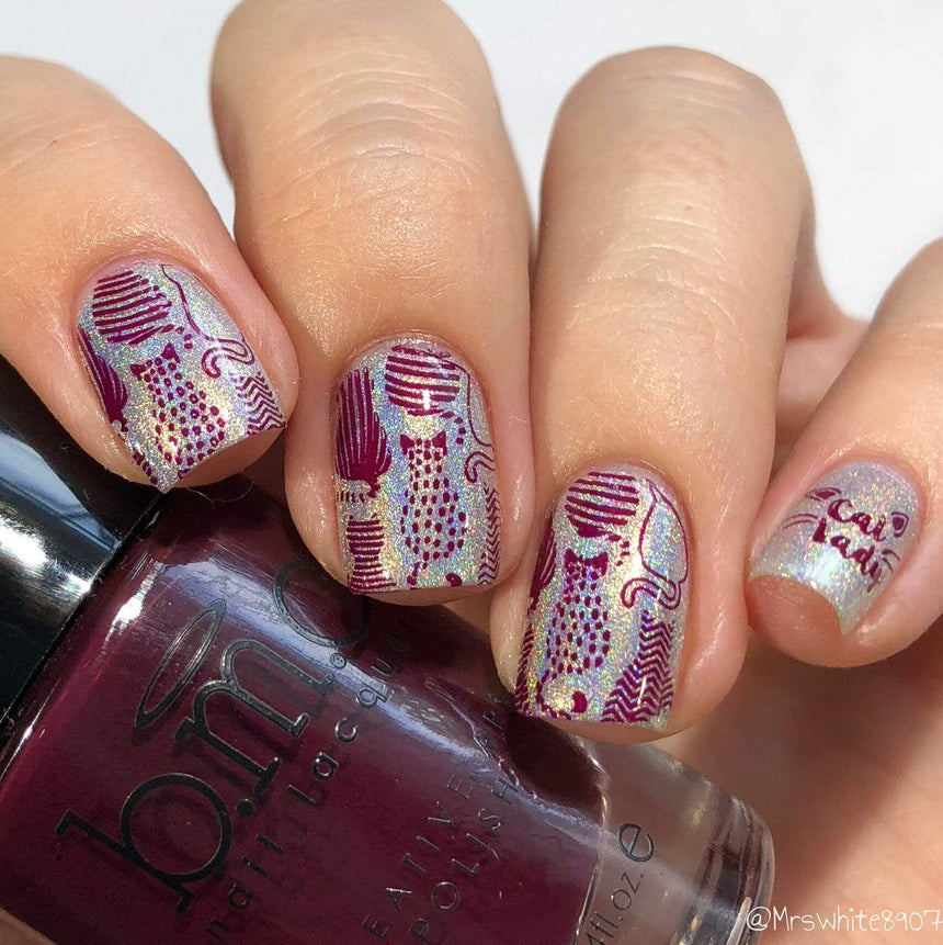 A manicured hand in glitters with cats design holding a polish.