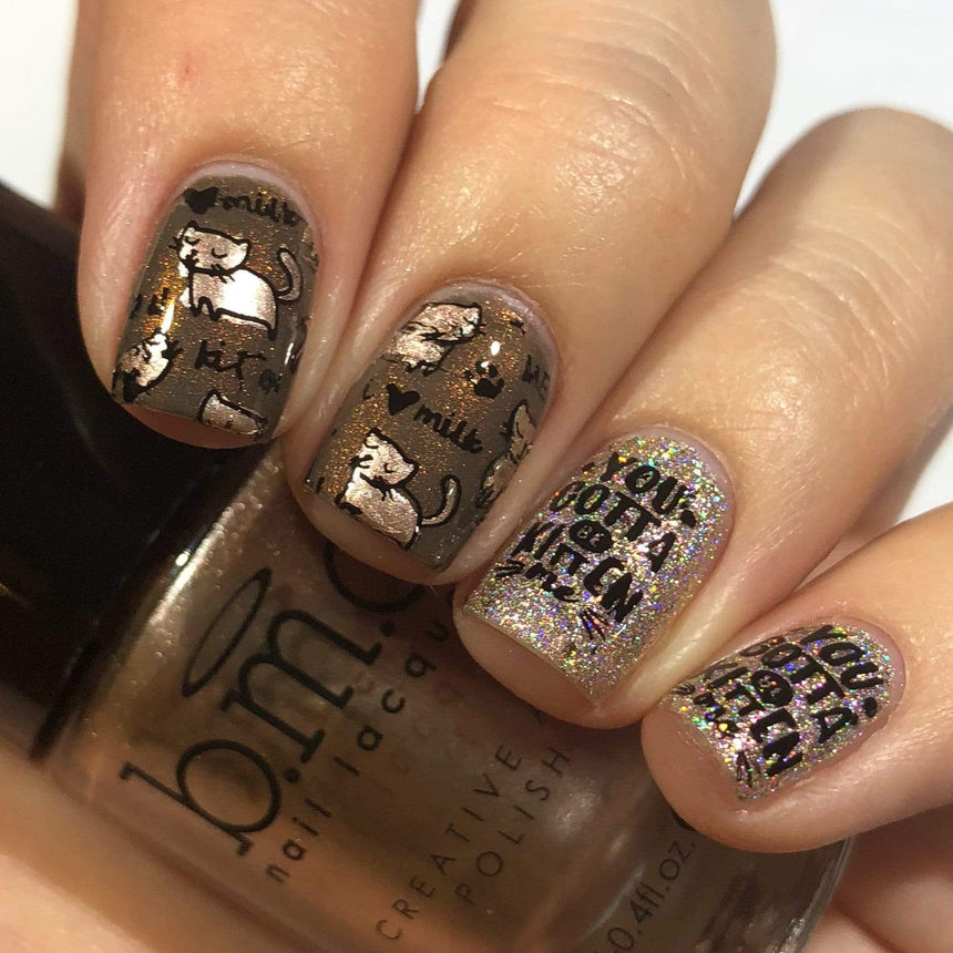 A manicured hand in glitters with cats design holding a polish.