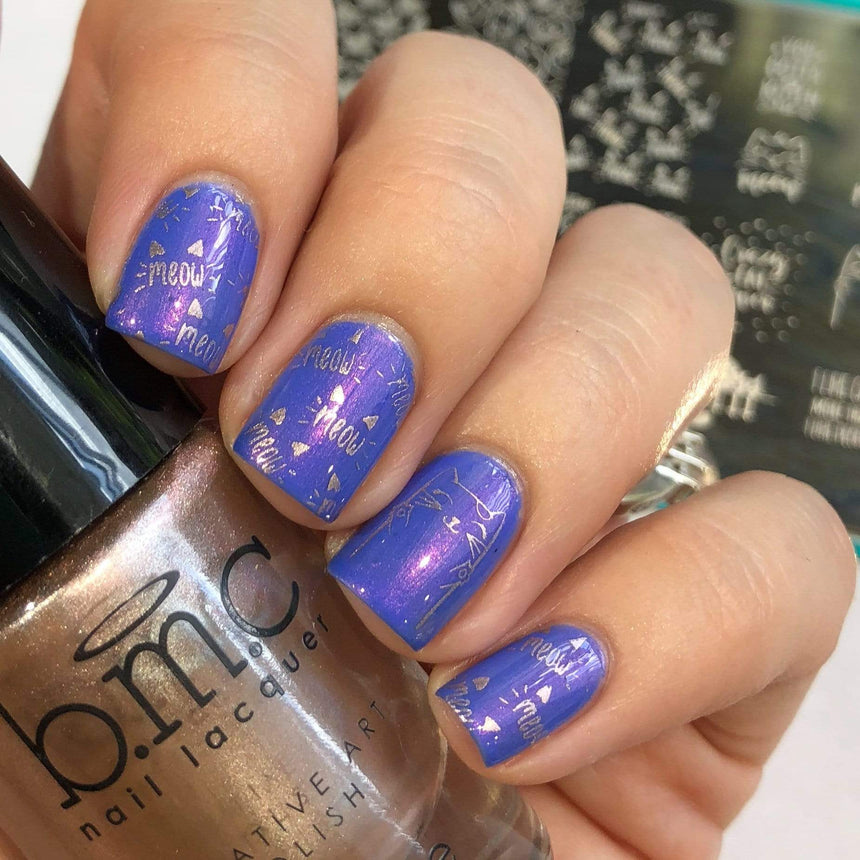 A manicured hand in blue with cats design holding a polish.