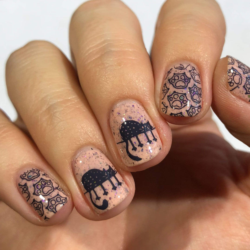 A manicured hand with cats and paws design by Maniology.