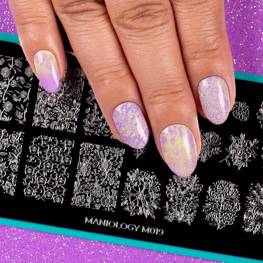 A manicured hand in purple with a garden variety design over a stamping plate.