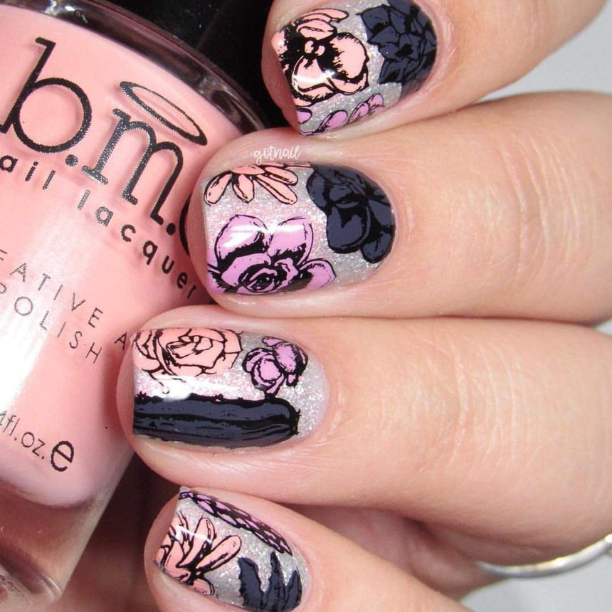 A manicured hand with flower designs in three different colors holding a polish.