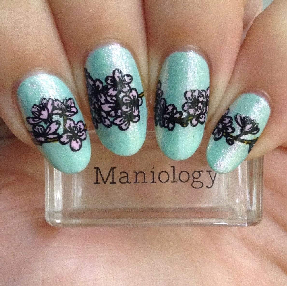 A manicured hand holding a stamper with a layered floral pattern designs.