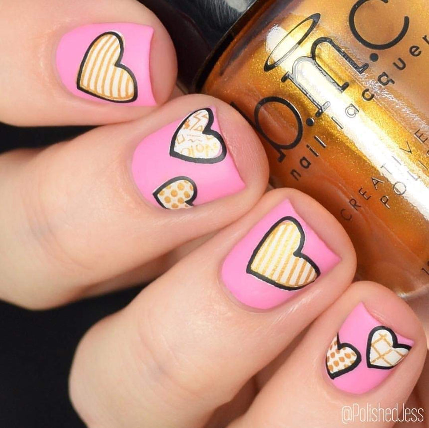 A manicured hand holding a Heart of Gold stamping polish