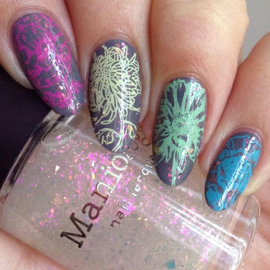 A manicured hand with floral designs holding a topper by Maniology (m179).