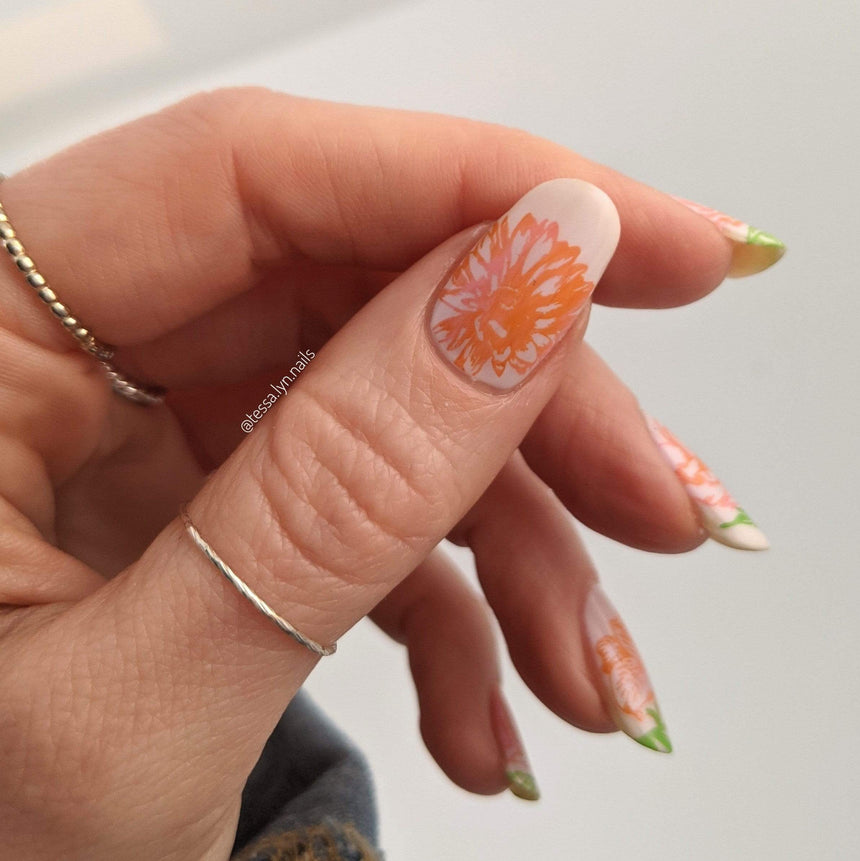 A manicured hand wearing a ring with floral designs by Maniology (m179).