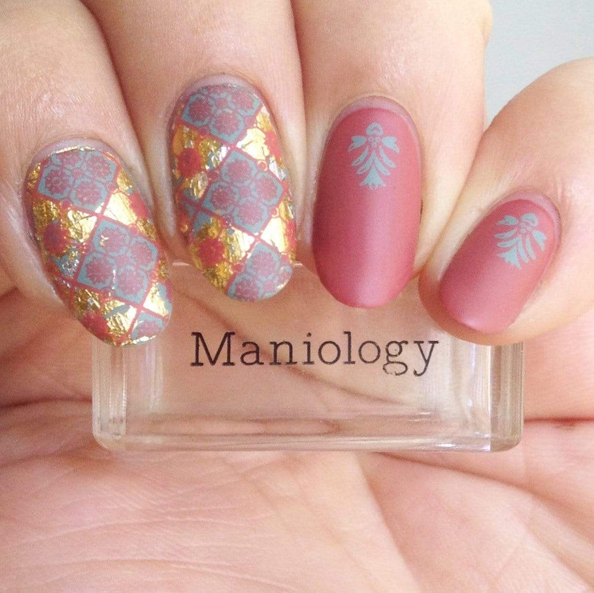 A manicured hand made with Terracotta Rose (B297) Light Red Stamping Polish holding a stamper by Maniology.