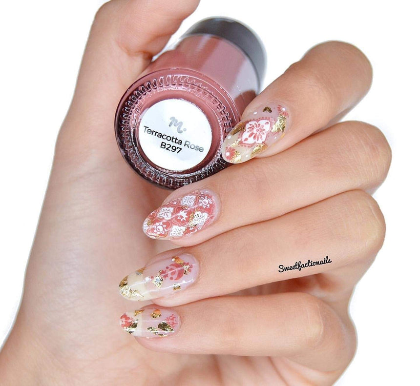 A manicured hand holding Terracotta Rose (B297) Light Red Stamping Polish by Maniology.