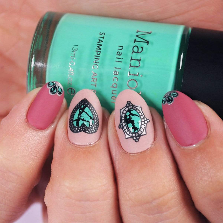 A manicured hand holding a Green Stamping Polish Turquoise (B324) by Maniology.