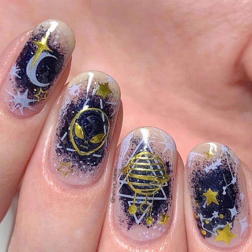 A manicured hand with stars, alien and moon designs.