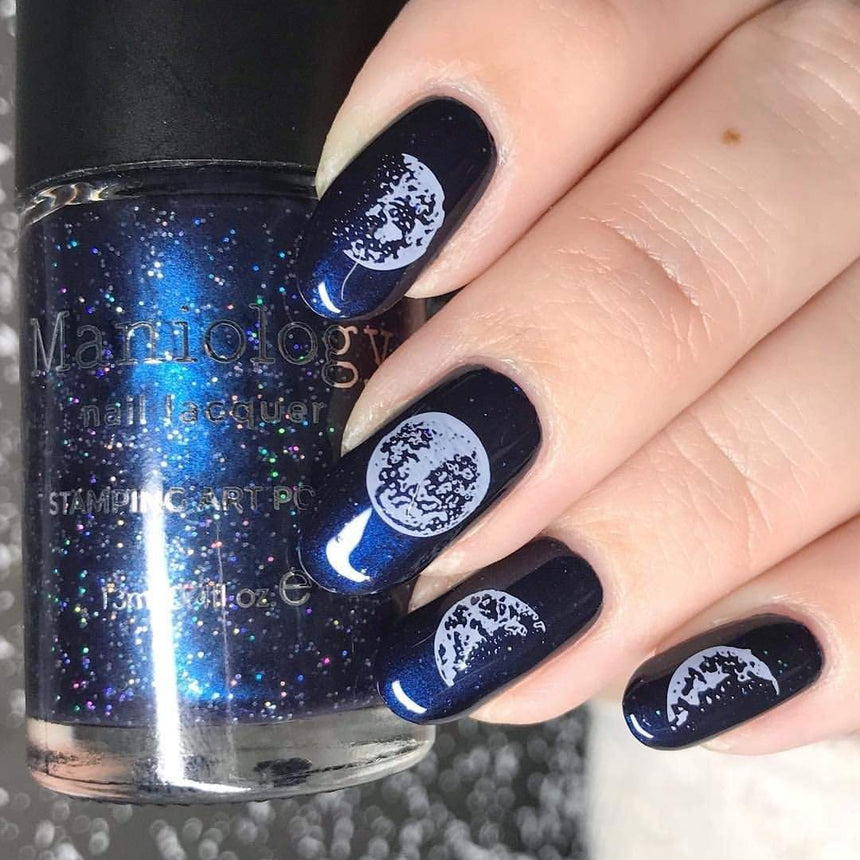 A manicured hand holding a Dark Navy Shimmer Stamping Polish by Maniology (B239).
