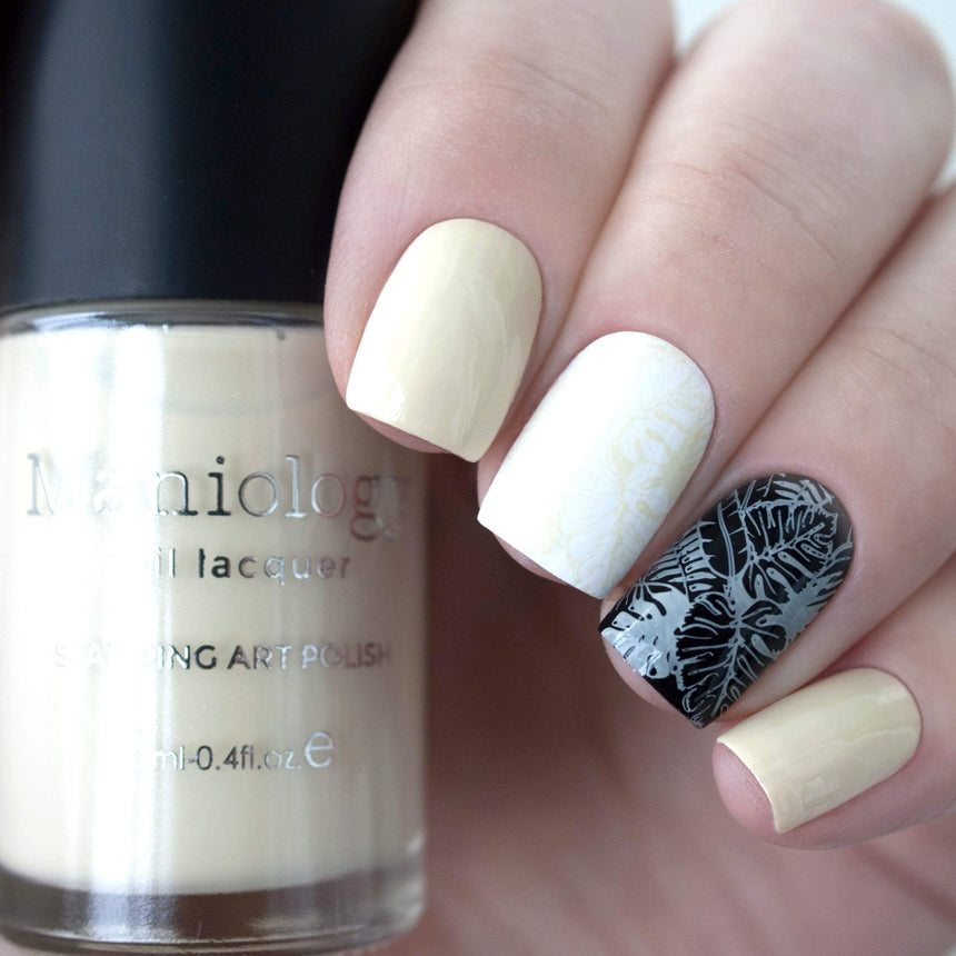 A manicured hand holding Creamy Custard Stamping Polish Coconut (B268) by Maniology.