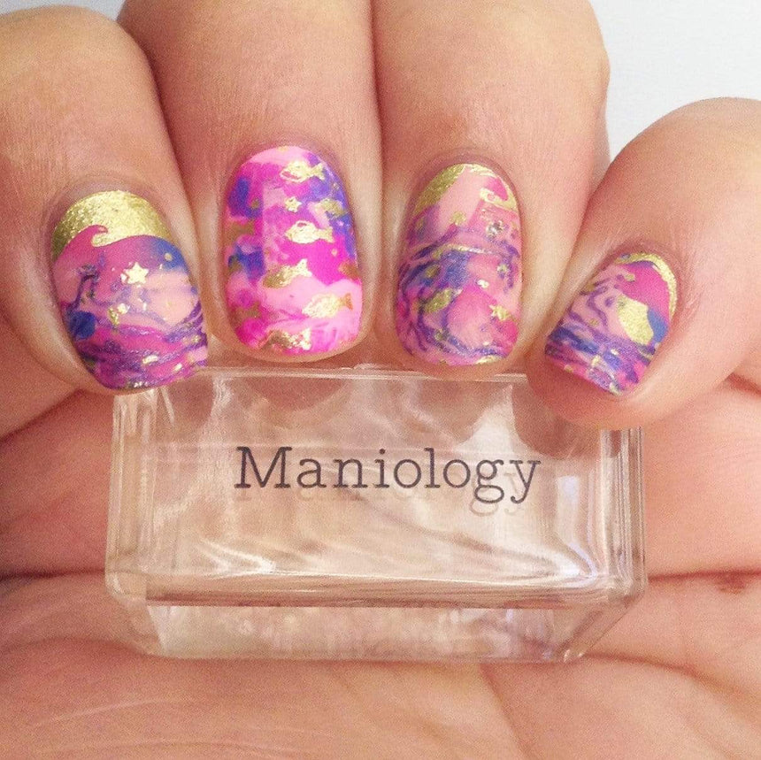 A manicured hand holding a stamper from Maniology.