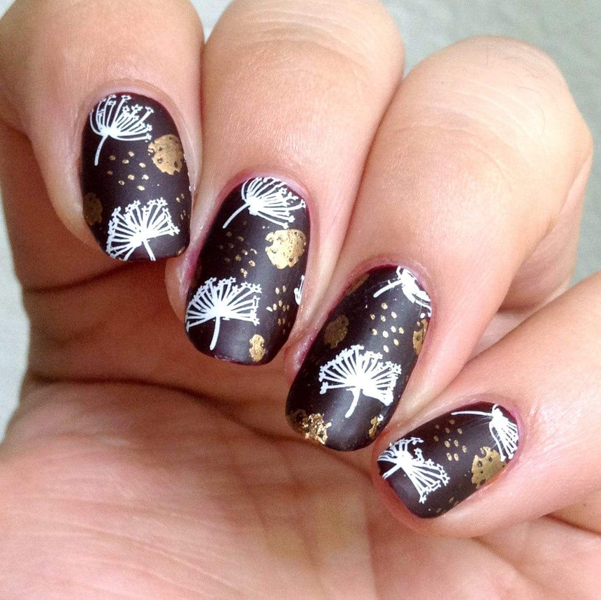 A manicured hand in black with a combination of Copper Orange Stamping Polish.