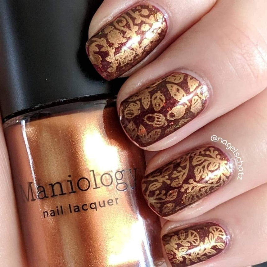 A manicured hand with Copper Orange Stamping Polish.