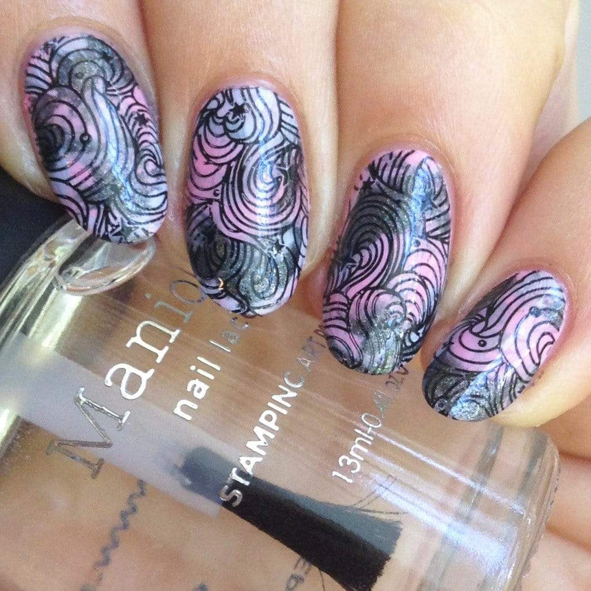 A manicured hand made with Black Magick (B293) Holographic Black Stamping Polish holding a top coat by Maniology.