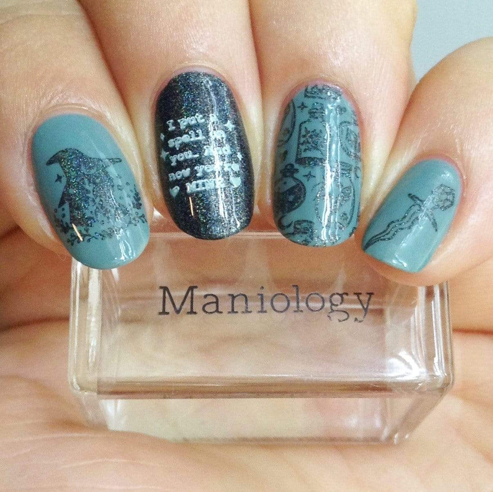 A manicured hand made with Black Magick (B293) Holographic Black Stamping Polish holding a stamper by Maniology.