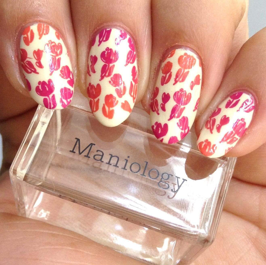A manicured hand with tulips design holding a stamper by Maniology (m048).