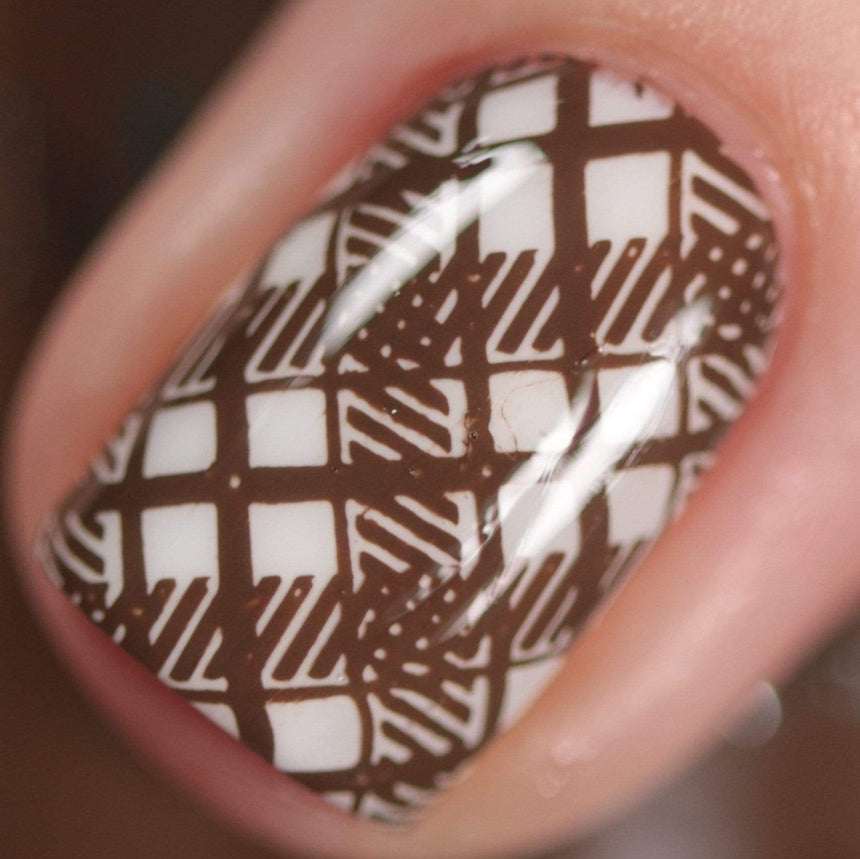 A manicured hand made with warm chocolate brown stamping polish from Sugar + Spice collection by Maniology (B351).