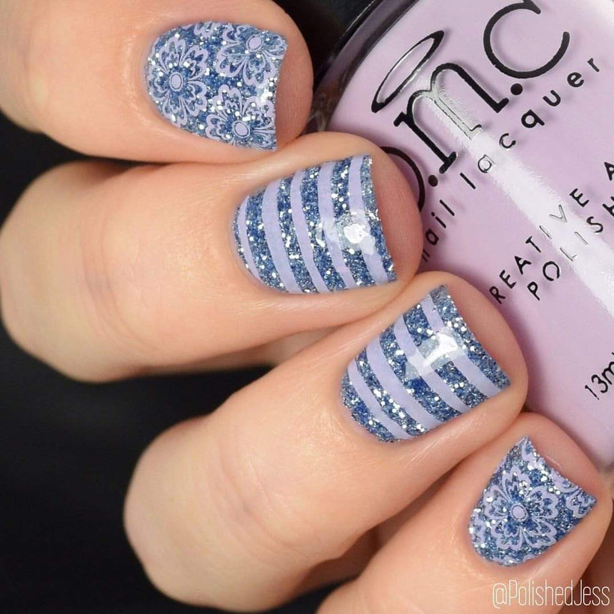 A manicured hand holding a light purple stamping polish by Maniology.