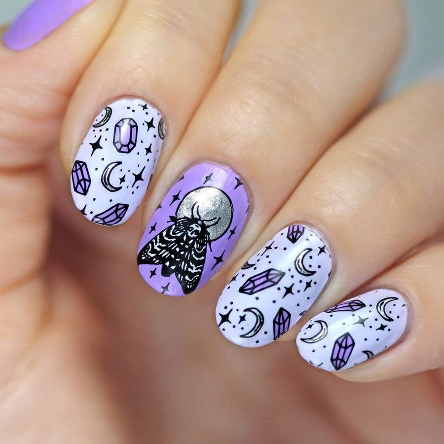 A manicured hand with moths, moon and crystals design by Maniology.