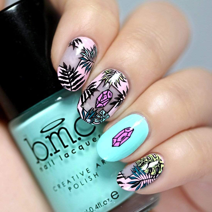 A manicured hand with crystals and leaves design holding a polish.