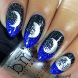 A manicured hand in blue and black with moon phases designs holding a polish.