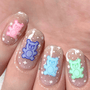 A manicured hand with a teddy bear in four colors and glitters design by Maniology.