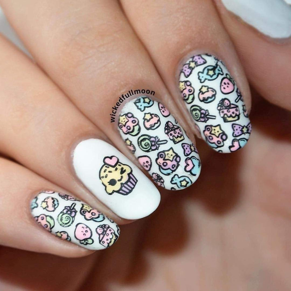  A manicured hand in white polish with cupcakes, stars, hearts, strawberries, ribbons, candy and lollipops design.