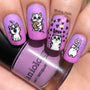 A manicured hand in purple with hearts and cuddle cats design holding a polish by Maniology.