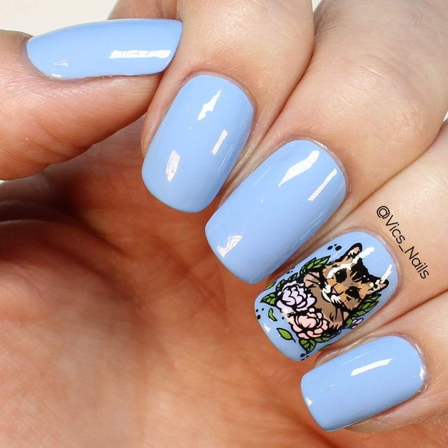 A manicured hand in blue with cat design by Maniology.