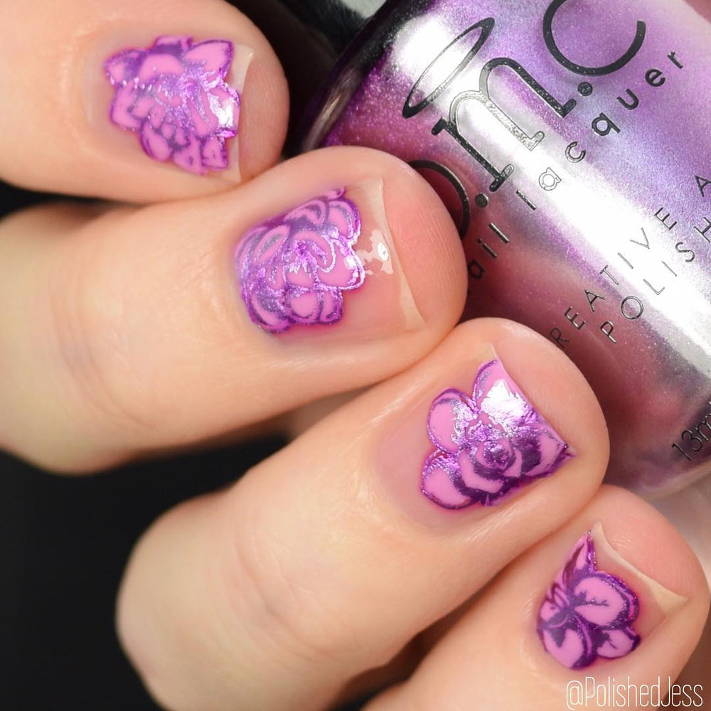 A manicured hand in purple with a flower design holding a polish.