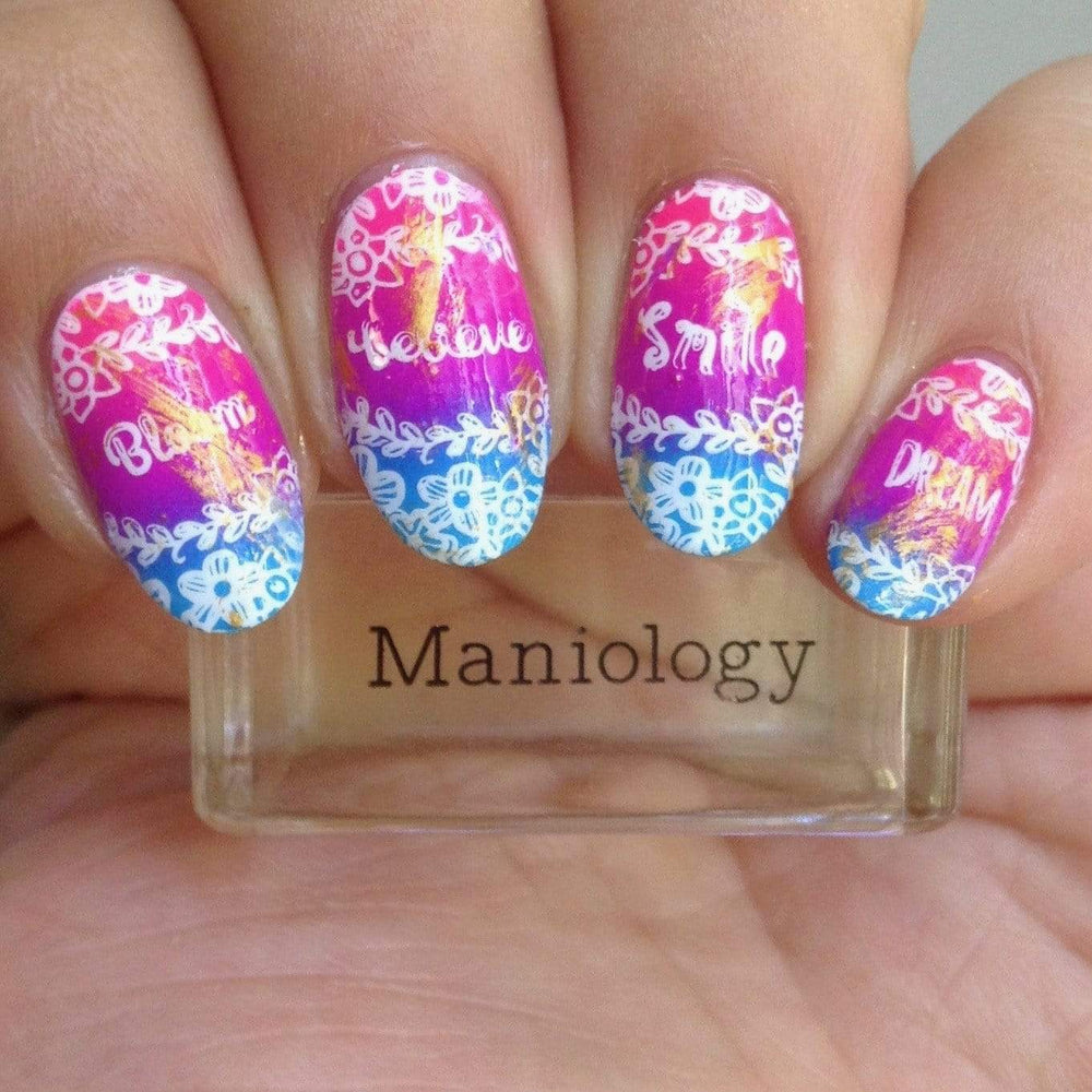  A manicured hand with inspirational words, and flowers designs by Maniology (m070) holding a stamper.