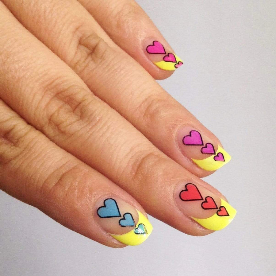 A manicured hand in yellow french tip design with hearts by Maniology (m052).