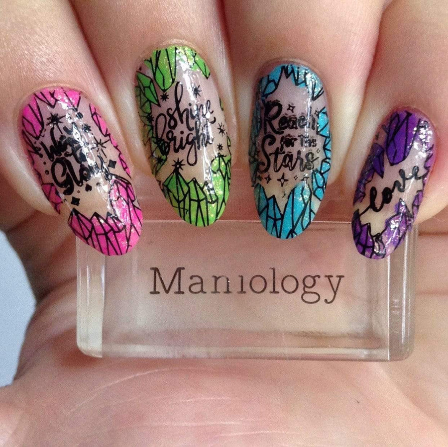 A manicured hand with Crystal Galaxy (m219) designs holding a stamper by Maniology.