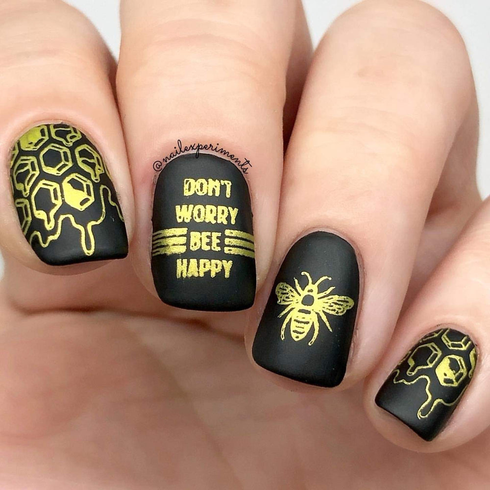 A manicured hand with experimental nail art in black with beehive and bee designs.