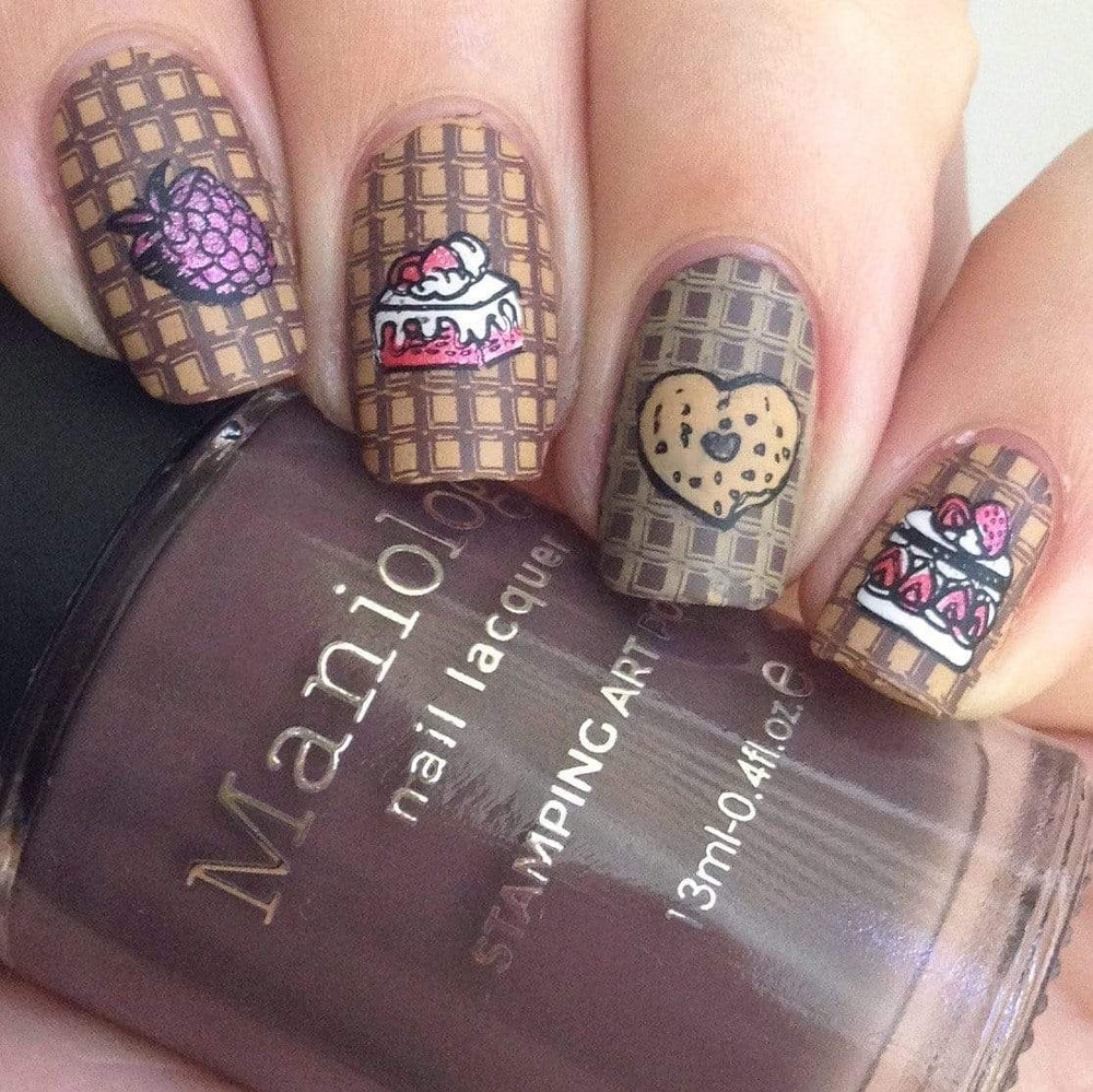  A manicured hand with cakes, cookie and pineapple designs by  Maniology (m100) holding a stamping polish.