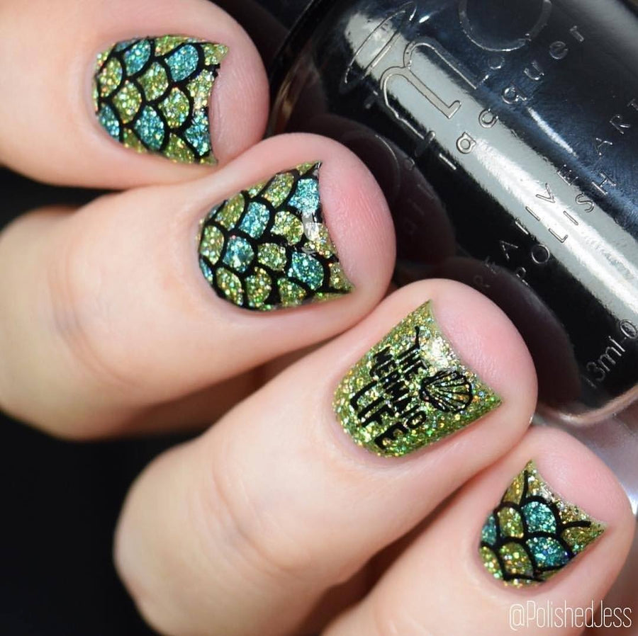 A manicured hand holding a Midnight Madness Blue Stamping Polish