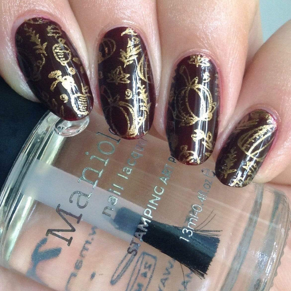 A manicured hand with pumpkins design holding a polish by Maniology (m164).