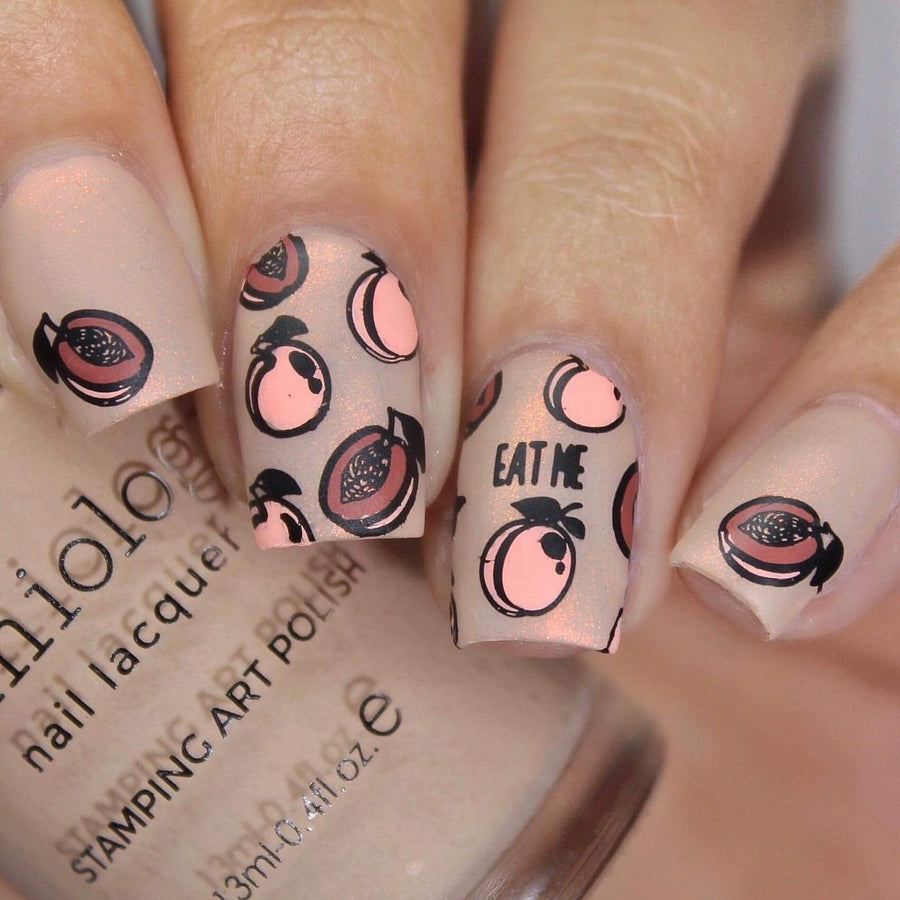 A manicured hand holding a polish by Maniology with some fresh fruit designs.