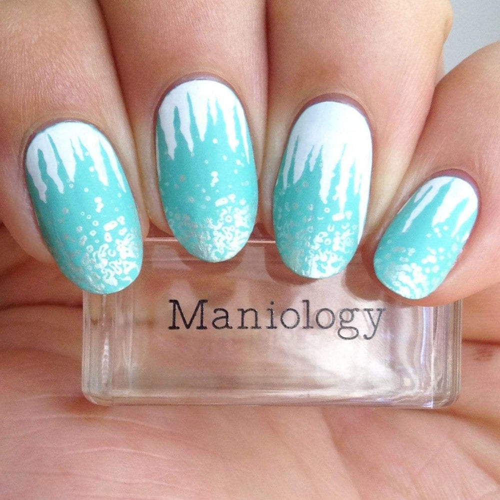 A manicured hand made with Frozen (B316) white stamping polish holding a stamper by Maniology.