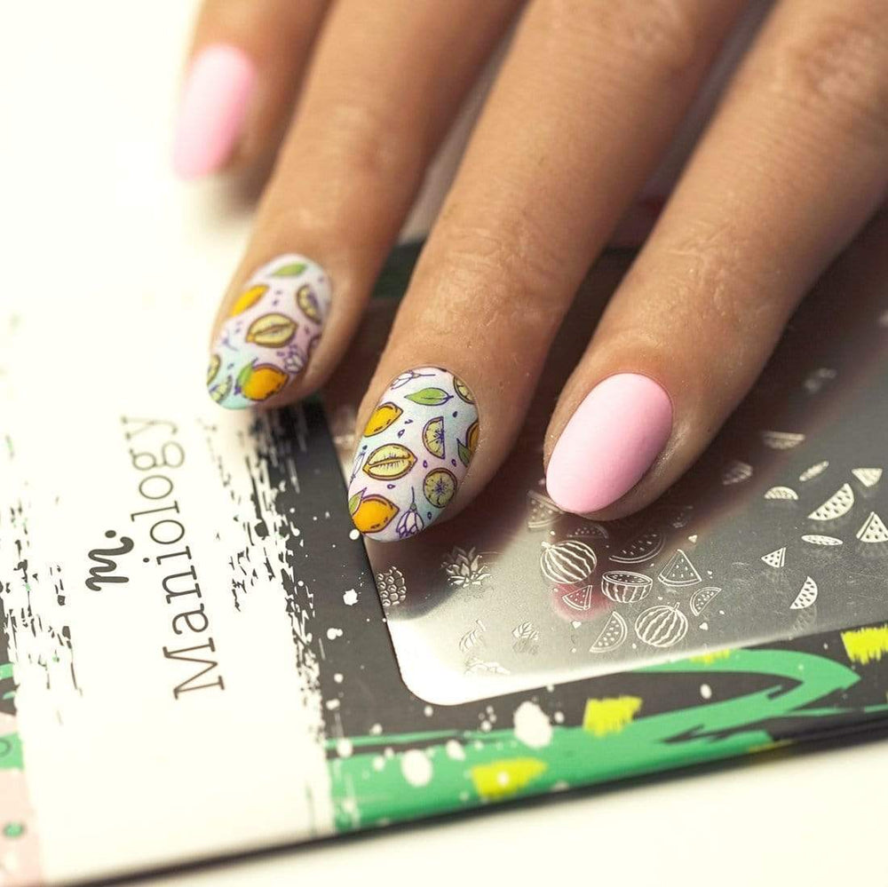 A manicured hand with layered fruit designs over a nail stamping plate by Maniology (m028).