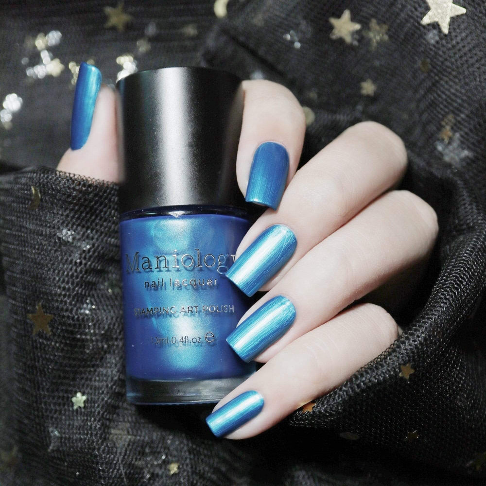 A manicured hand holding a Glass Slipper - Blue Duochrome Stamping Polish by Maniology.