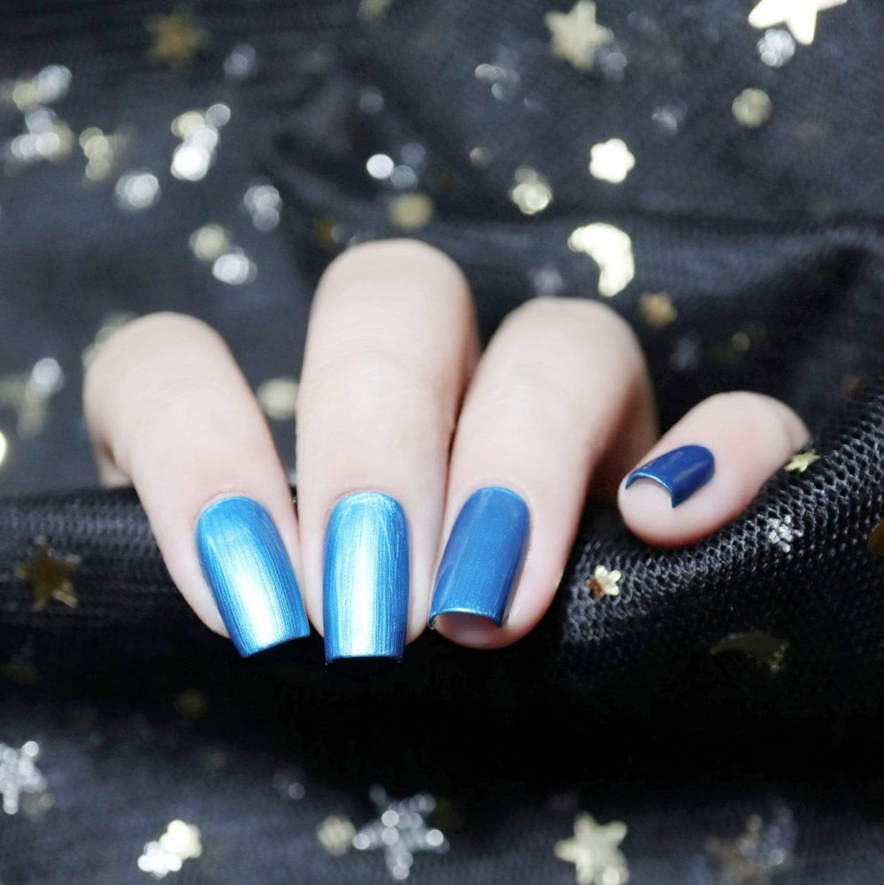 A manicured hand with the use of Glass Slipper - Blue Duochrome Stamping Polish by Maniology.