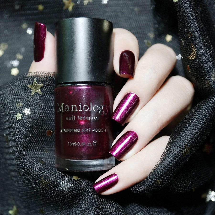 A manicured hand holding a Wolfish - Plum Duochrome Creative Art Stamping Polish by Maniology.