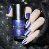 A manicured hand holding a Gretel Brittle - Indigo Duochrome Stamping Polish by Maniology.