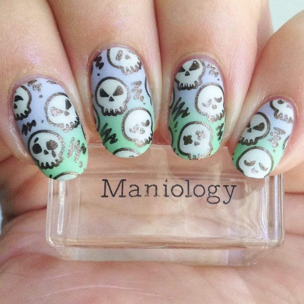 A manicured hand with skulls design holding a stamper by Maniology (m158).