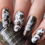 A manicured hand in black and white with bad to the bones designs holding a stamping polish by Maniology.