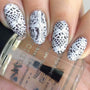 A manicured hand with Knotty by Nature stamping plate designs holding a top coat by Maniology (m177).