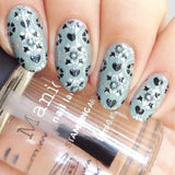  A manicured hand made with Shangri La (B296) Dusty Blue Stamping Polish holding a top coat by Maniology.